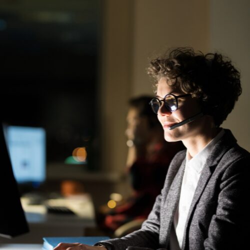 Customer service representative with headset smiling at computer screen