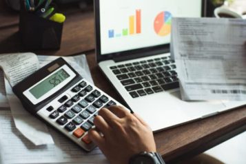 Blogformaat-3-768×432 Person sitting at a desk with a laptop, a piece paper and a calculator