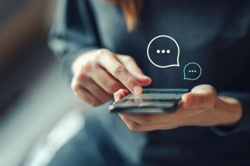 Blogfotos-Minty-2-1-1536×864 Person holding a mobile phone with two chat icons above it