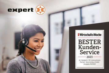 Customer service representative with headset smiling at computer screen with Expert logo in top left corner